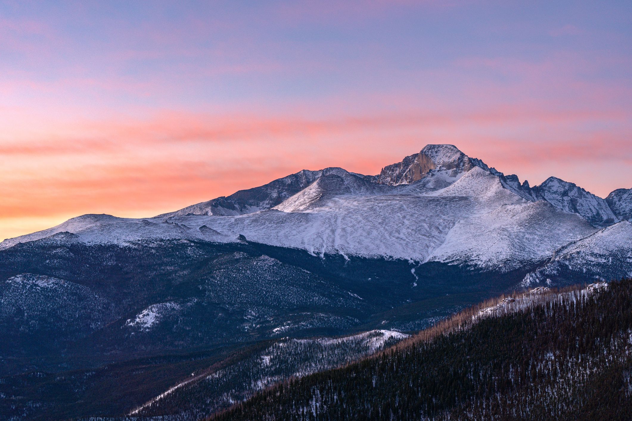 Snowy mountain landscape at sunset with vibrant sky.