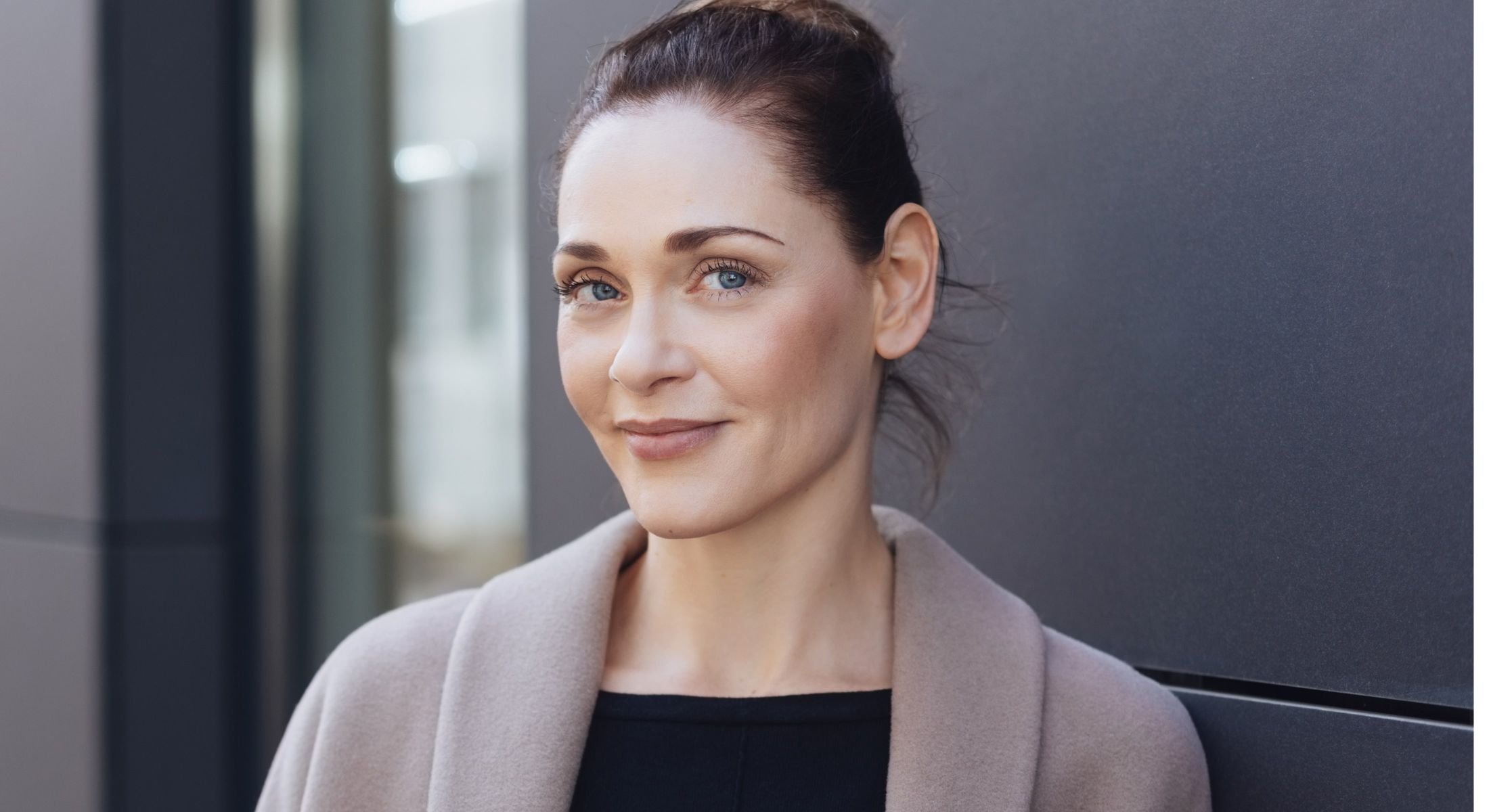 Woman smiling against a modern background.